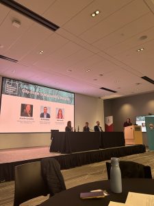 Four presenters at a table in front of a screen.